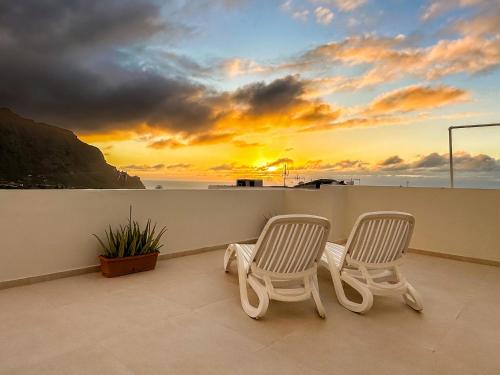 two chairs sitting on a balcony with a sunset at Sunset Terrace Studio - Ocean View - Top Floor in Buenavista del Norte