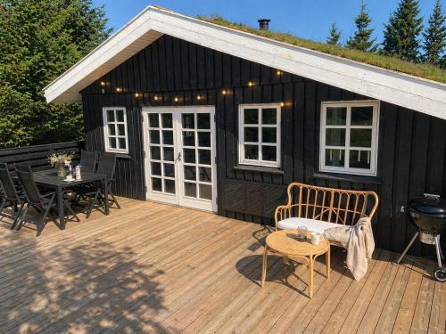 a black cabin with a deck with a table and chairs at Cozy child-friendly house in Blokhus