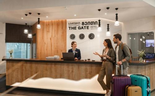 a group of people standing at a counter with luggage at The Gate Hotel City Centre in Tbilisi City