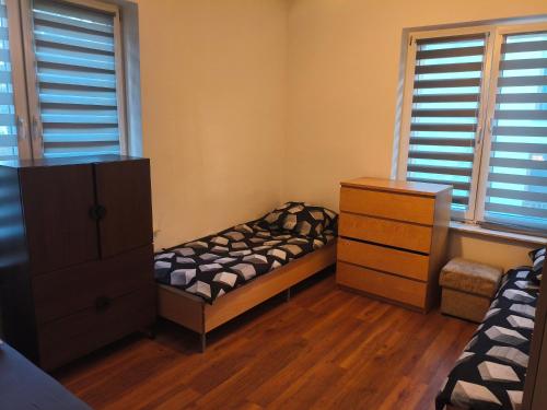 a bedroom with a bed and a dresser and windows at Hostel Tet6 in Gdynia