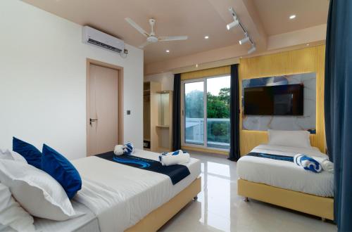 a bedroom with two beds and a flat screen tv at Ocean Bounty in Ukulhas