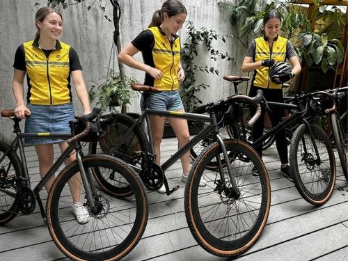 three girls are standing next to their bikes at Wanderlust District in Mexico City
