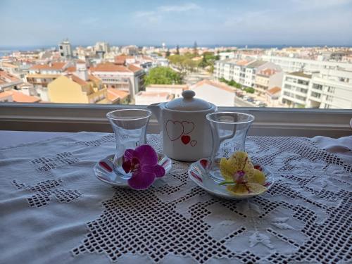 a table with two glasses and a tea pot on a table with a window at Minha Alegre Casinha in Sines