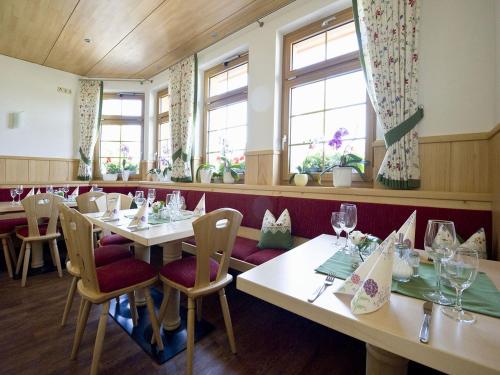 restauracja z białymi stołami, krzesłami i oknami w obiekcie Gasthaus Schweizerhof w mieście Titisee-Neustadt