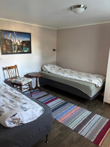 a bedroom with two beds and a chair and a table at Strand huset in Hitra