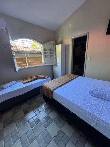 a bedroom with two beds and a window at Pousada Pedra que Canta in Itamaracá