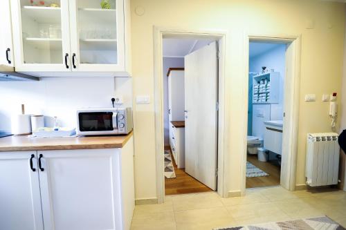 a kitchen with white cabinets and a microwave at BellaVita Apartman in Vrnjačka Banja