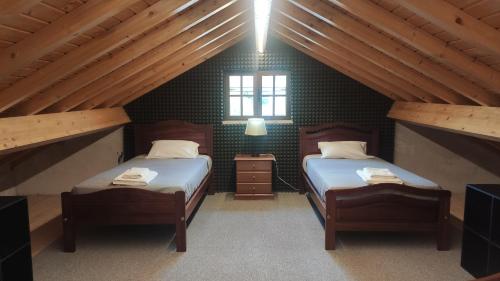 a attic room with two beds and a window at Casa do Vô Sousa in Pombal