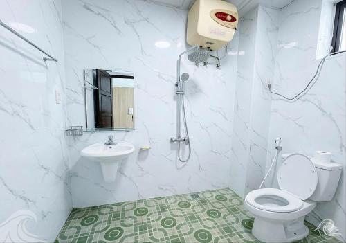 a white bathroom with a toilet and a sink at Khách sạn Hồ Gươm in Sầm Sơn
