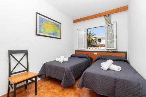 two beds in a room with two windows at Bon repós B5 in Cala en Bosc