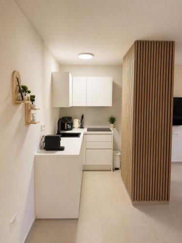 a small kitchen with white cabinets and a wooden wall at NAIA apartment in Koper