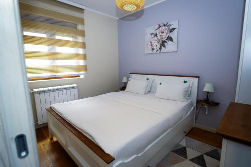 a bedroom with a bed with white sheets and a window at BellaVita Apartman in Vrnjačka Banja