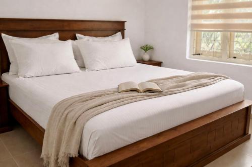 a bedroom with a bed with a book on it at Luminosium Nature Retreat & Heritage Forest Garden in Pannala