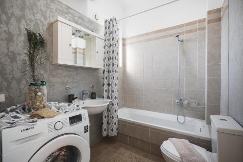 a bathroom with a washing machine next to a bath tub at Royal Touch Suite in Loutra