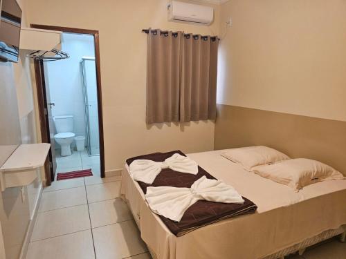 a bedroom with a bed and a bathroom at Vila Santa Hotel in Aparecida