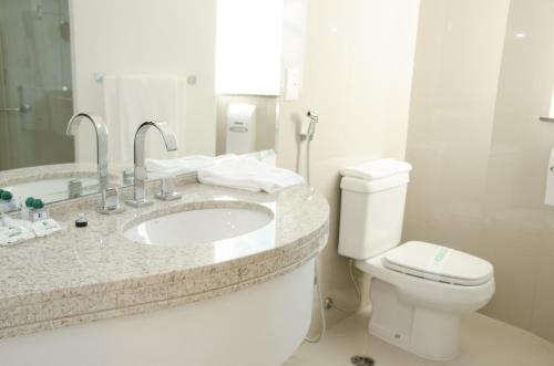 a white bathroom with a sink and a toilet at Hotel Boulevard in Londrina