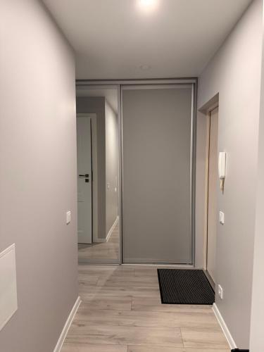 an empty hallway with a large glass door with a mat at Apartment Ventos 55 in Mažeikiai