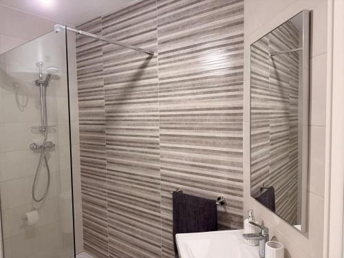 a bathroom with a shower with a sink and a mirror at 11 Rose in Sannat