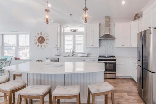 a kitchen with white cabinets and a white island with stools at The Royal Treat in Lavallette
