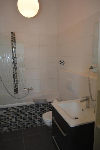 a bathroom with a sink and a toilet and a light at Entre Deux Pays Apartments in Spa