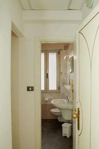 a white bathroom with a sink and a toilet at B&B Metropols Sottomarina in Sottomarina