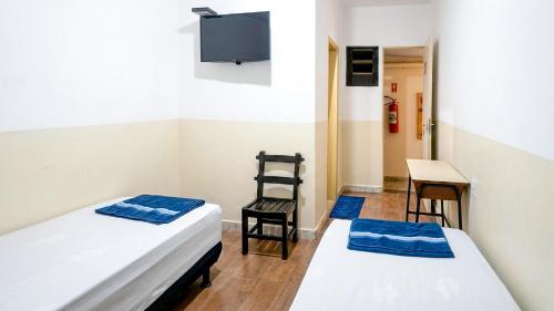 a room with two beds and a table and a chair at Hospedaria Barão in Campinas