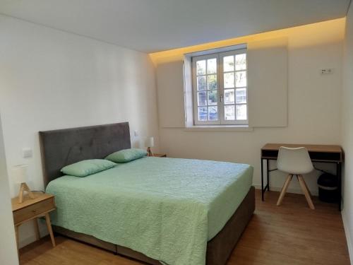 a bedroom with a bed and a desk and a window at 4-As Andar-Moradia Muralhas in Guimarães