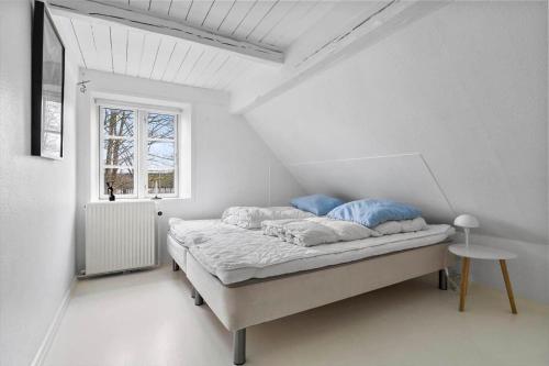 a white bedroom with a bed and a window at 20229-Samso-Byvejen-20 in Hårdmark