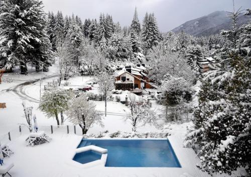 a swimming pool covered in snow next to a house at Hostería Verde Morada in Villa La Angostura