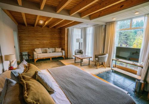 a bedroom with a large bed and a living room at Hostería Verde Morada in Villa La Angostura