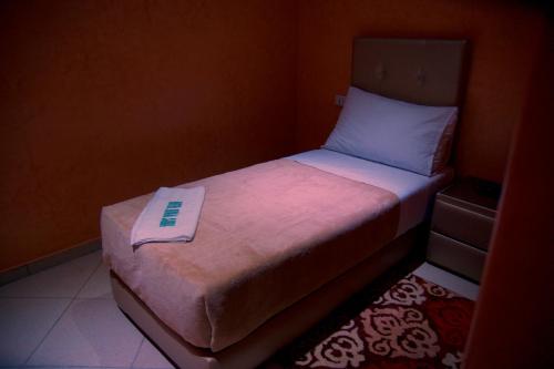 a small bed with a book sitting on top of it at Hotel Rimal Sahara in Laayoune