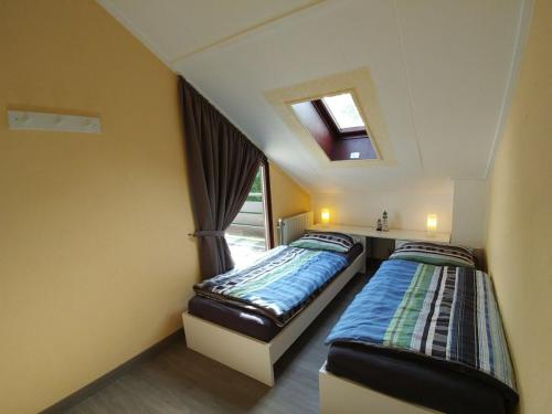 two beds in a small room with a window at Rustpunt in Brouwershaven