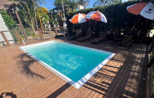 a swimming pool with two umbrellas on a deck at Pousada Cacau in Praia do Rosa
