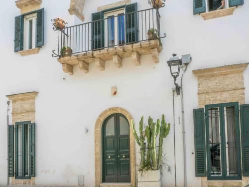 a white building with a green door and a balcony at Palazzo Vaglio in Alliste