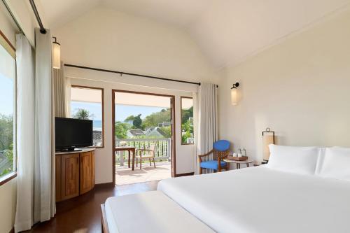 a bedroom with a bed and a television and a balcony at Centara Villas Phuket in Karon Beach