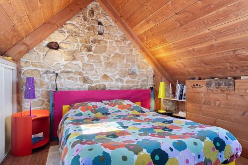 a bedroom with a bed and a stone wall at Chez Fred proche plage et gr34 in Plougoulm
