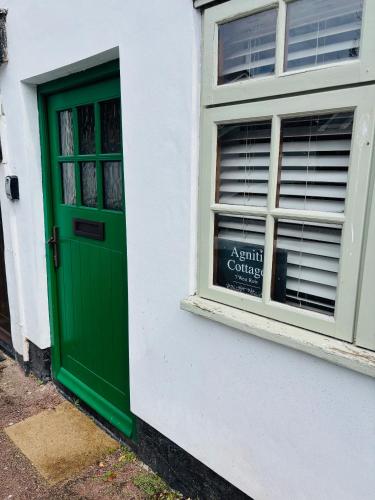 a green door on a white building with a window at Agniti Cottage in Derby