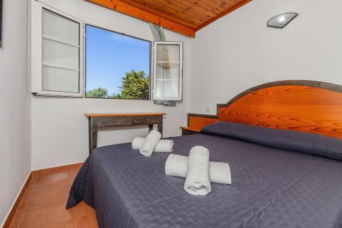 a bedroom with a blue bed with white towels on it at Bon repós B11 in Cala en Bosc
