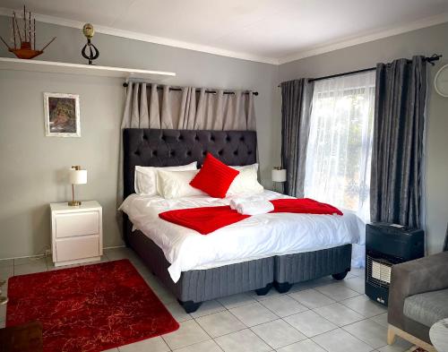 a bedroom with a large bed with red pillows at Pinnacle Pearl View Cottage in Johannesburg