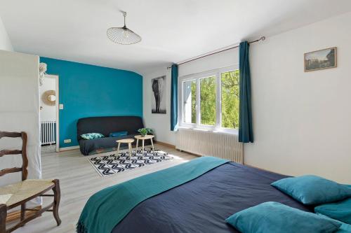 a bedroom with blue walls and a bed and a chair at Gîte De L'etrie in Mauves-sur-Loire