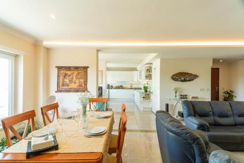 a dining room and living room with a table and a couch at Family Comfort House in Seixal