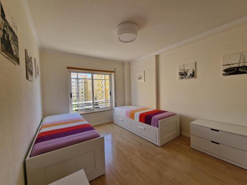 a bedroom with two beds and a window at Family Comfort House in Seixal