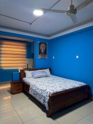 a blue bedroom with a bed and a blue wall at 247Hotel Apartments in Accra