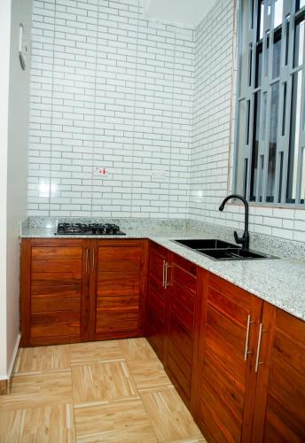 a kitchen with wooden cabinets and a sink at Be Home Apartments in Nkoanrua