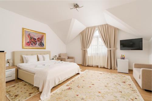 a white bedroom with a bed and a tv at Tudor Central House Sibiu - Garden, Parking, Quiet Area in Sibiu