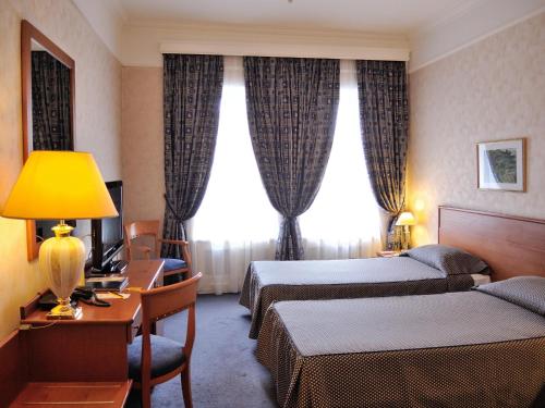 a hotel room with two beds and a desk at Grand Hotel Ukraine in Dnipro