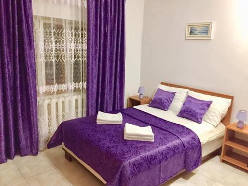 a bedroom with purple curtains and a purple bed at Casa Dorului in Mangalia