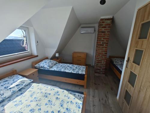 a attic bedroom with two beds and a window at Domek na Górce 2 in Krościenko
