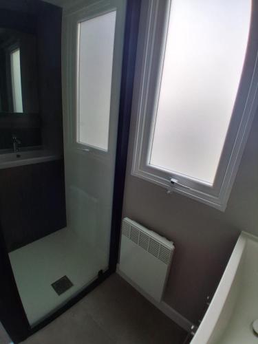 a bathroom with a shower with a window and a sink at Mobil home 590 in Pont-Aven
