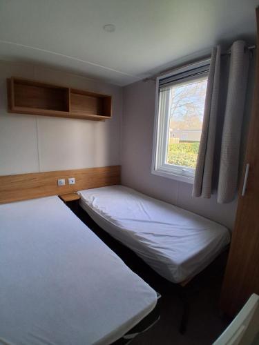 two beds in a small room with a window at Mobil home 590 in Pont-Aven
